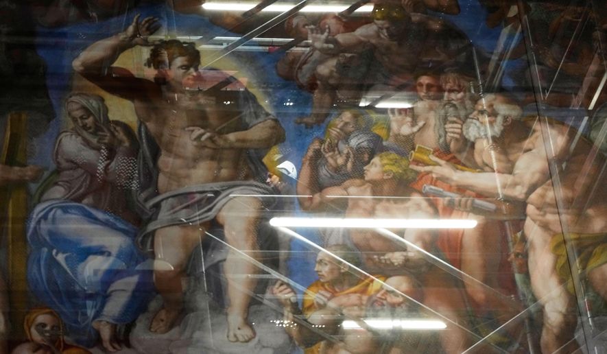 A woman walks behind a screen with a replica of “The Last Judgment,”superimposed on it that covers the scaffolding used for its extraordinary maintenance during a presentation for press in the Sistine Chapel at the Vatican, Saturday, Feb. 28, 2026. (AP Photo/Alessandra Tarantino)