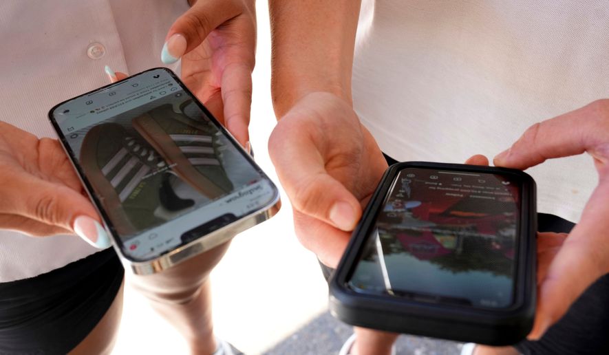 Young people use their phones to view social media in Sydney, Nov. 8, 2024. (AP Photo/Rick Rycroft, File)