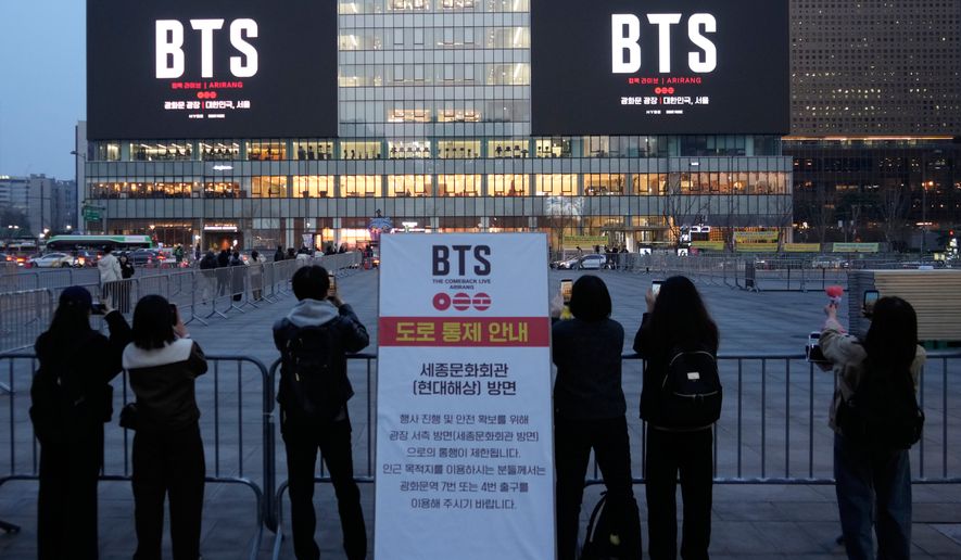 People take photos of screens promoting a comeback concert of K-pop group BTS at Gwanghwamun Square in Seoul, March 17, 2026. (AP Photo/Ahn Young-joon)