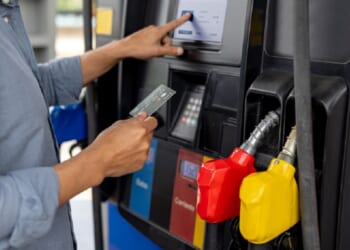 A man uses a credit card to pay for gas at a gas station.