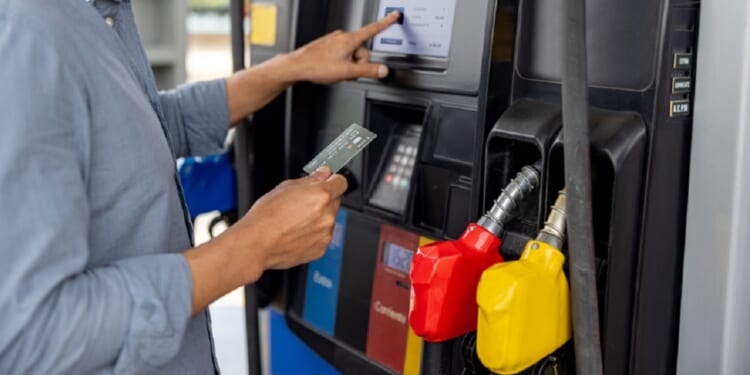 A man uses a credit card to pay for gas at a gas station.
