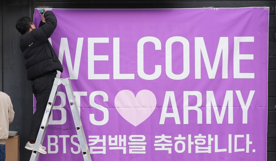 A man hangs a banner at a convenience store near the stage for a free concert by K-pop group BTS in Seoul, South Korea, March 18, 2026. (AP Photo/Lee Jin-man)