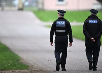 Police officers approach the gates of the Royal Lodge, Andrew Mountbatten-Windsor's former residence in Windsor Great Park, on Feb. 20, 2026, in Windsor, England.