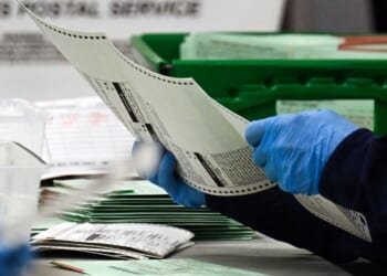 An election worker removes a ballot from an envelope to count and inspect the pages inside the Maricopa County Tabulation and Election Center on Election Day, Nov. 5, 2024, in Phoenix, Arizona.