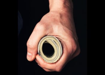 A man holds a wad of cash tightly.