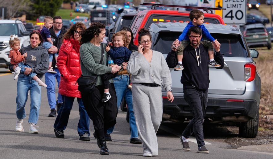 Law enforcement escort families with children away from the Temple Israel synagogue Thursday, March 12, 2026, in West Bloomfield Township, Mich. (AP Photo/Paul Sancya)