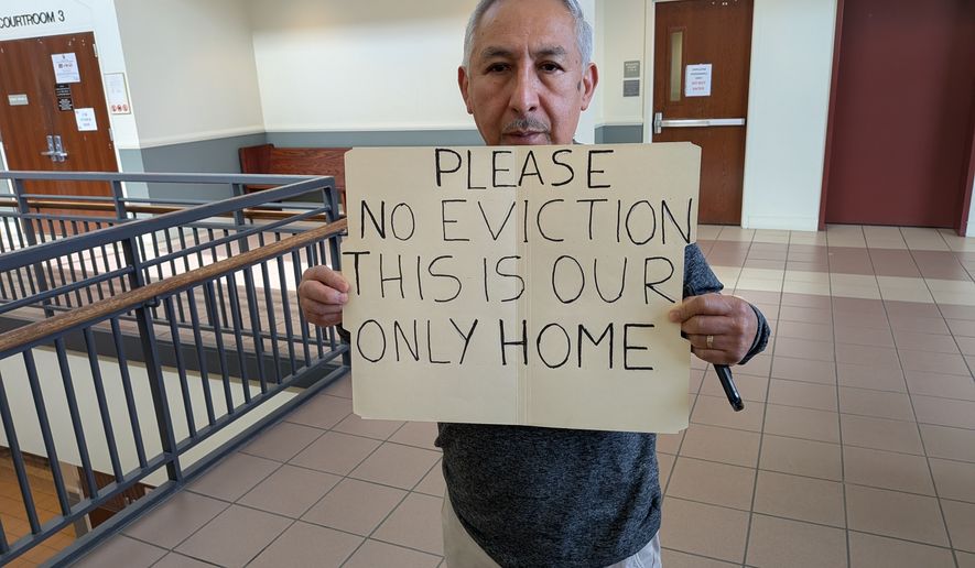 Rolando Lopez, a unit owner at the Marylander Condominiums, holds a sign he brought to protest Prince George's County efforts to evacuate him at a Maryland District Court hearing in Hyattsville on Tuesday, March 17, 2026. Residents have been ordered to evacuate the property because its heating system has not worked since vagrants damaged a boiler in late November. (Sean Salai/The Washington Times)