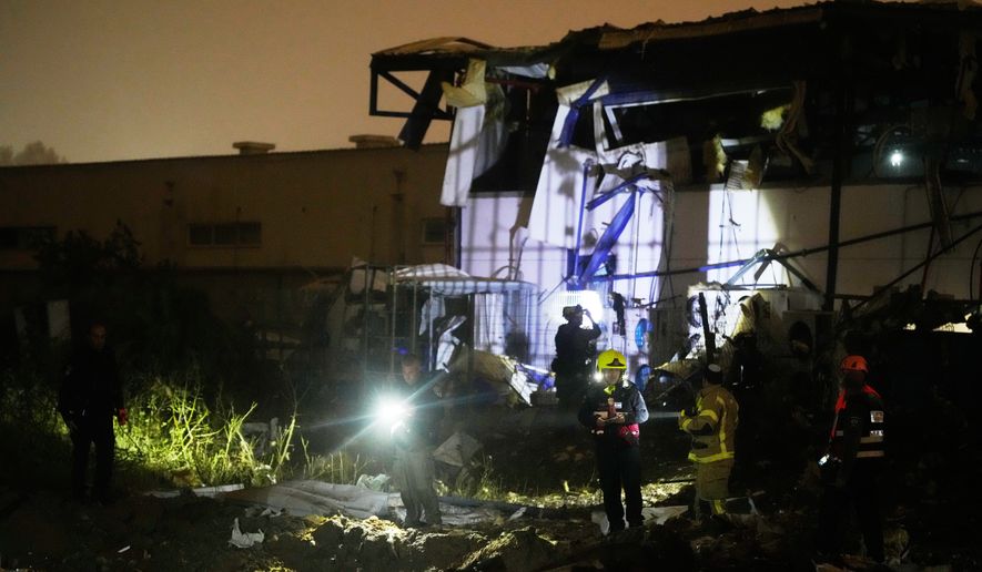 Israeli security forces and rescue teams inspect a site struck by an Iranian missile in Petah Tikva, Israel,Thursday, April 2, 2026. (AP Photo/Ohad Zwigenberg)