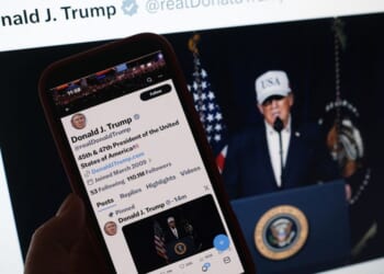 A person looks at President Donald Trump's social media accounts on a computer screen and a phone screen at the same time on Feb. 28, 2026.
