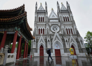 A man walks out from a pavilion near the Xishiku Catholic Church during a rainy day in Beijing, May 9, 2025.