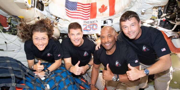 The Artemis II crew pose for. a photograph inside the Orion spacecraft on their way home from the far side of the Moon on April 6, 2026.