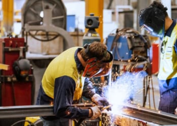 Workers wear protective gear as they use heavy machinery.