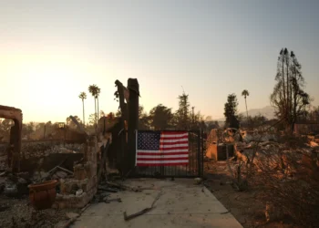 An American flag hangs on the fence of a scorched home in Altadena, California on January 10, 2025