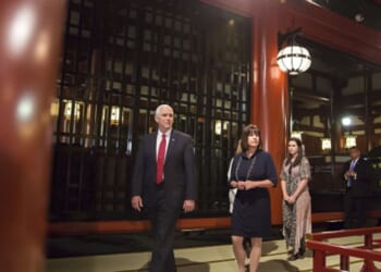 Mike Pence walks in Japan flanked by team members on April 18, 2017.