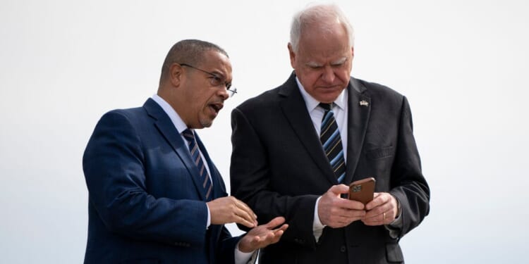 Minnesota Governor Tim Walz and Minnesota Attorney General Keith Ellison await the arrival of then-U.S. Vice President Kamala Harris at the Minneapolis-St. Paul International Airport in Saint Paul, Minnesota, on March 14, 2024.