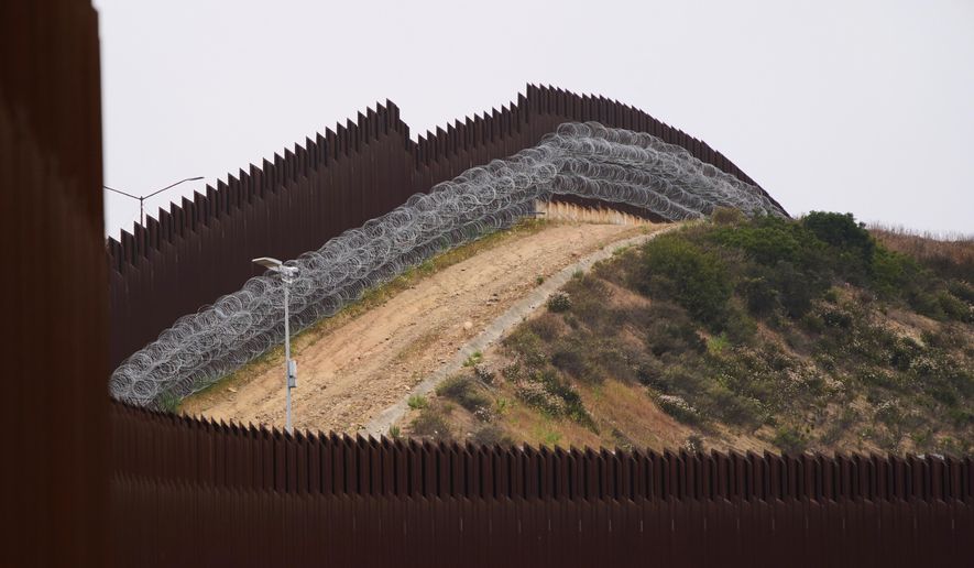 Concertina wire lines the interior of a border wall separating Tijuana, Mexico, from the United States, June 4, 2025, in San Diego. (AP Photo/Gregory Bull, File)