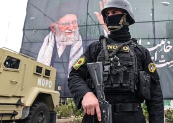 A member of the Iranian security forces stands guard next to a banner honoring Iran's slain supreme leader Ayatollah Ali Khamenei in Tehran on Tuesday.