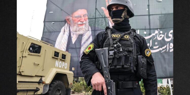 A member of the Iranian security forces stands guard next to a banner honoring Iran's slain supreme leader Ayatollah Ali Khamenei in Tehran on Tuesday.
