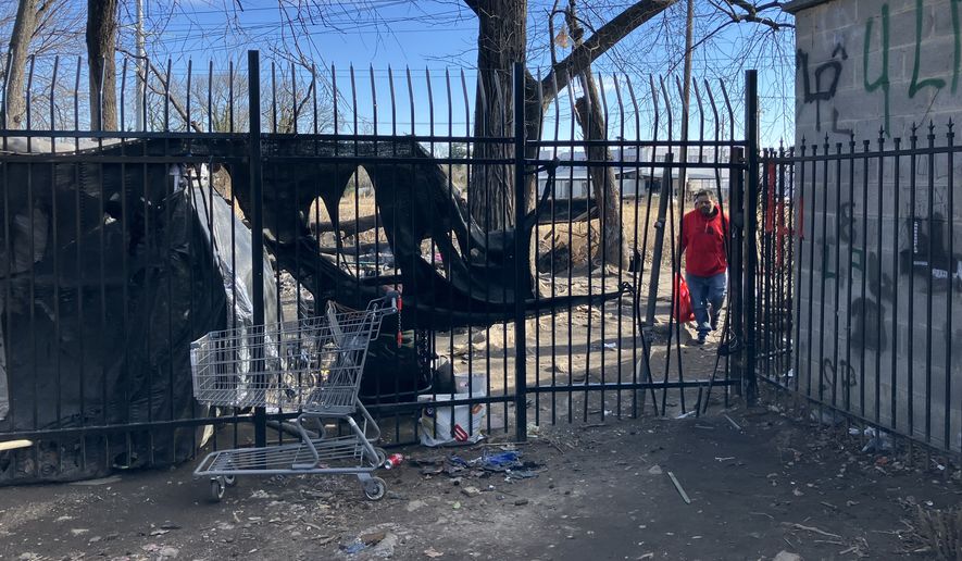 Unidentified people are seen at the Marylander Condominiums through a gap in the security fence on Monday, Jan. 12. Property managers say homeless people created the opening when workers installed the fence last year. (Sean Salai/The Washington Times)