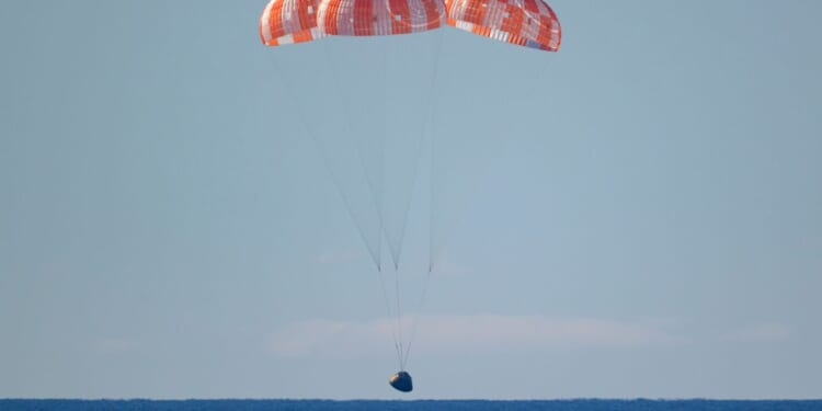 In this handout photo provided by NASA, NASA's Orion spacecraft with Artemis II crewmembers NASA astronauts Reid Wiseman, commander; Victor Glover, pilot; Christina Koch, mission specialist; and Canadian Space Agency astronaut Jeremy Hansen, mission specialist aboard is seen under parachutes as it lands in the Pacific Ocean off the coast of California on April 10, 2026.