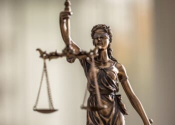 Lady Justice bronze statuette stands with the weight scales of Justice.