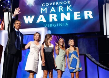 In a 2008 file photo, former Virginia Gov. Mark Warner waves from the stage with his wife, Lisa Collis, and daughters Eliza, Gillian, and Madison during day two of the Democratic National Convention in Denver, Colorado.