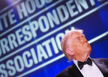 President Trump in profile in bottom right of shot underneath large "White House Correspondents' Dinner" sign.