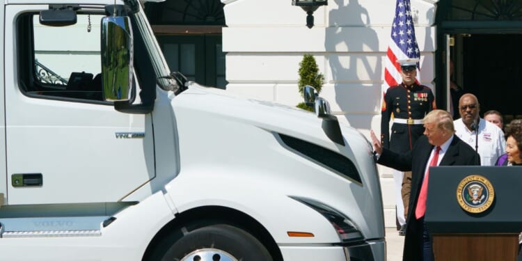 President Donald Trump reaches out to pat the hood of a truck at an event to celebrate America's Truckers at the White House in Washington, DC on April 16, 2020.