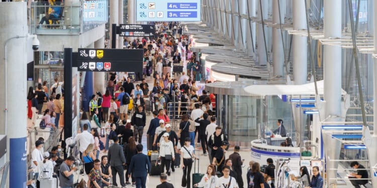 Passengers walk through a busy airport
