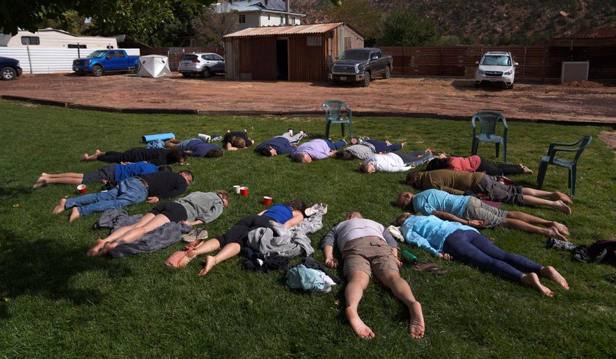 Participants lay face down on the grass during an integration circle at an ayahuasca retreat in Hildale, Utah, Oct. 15, 2022. (AP Photo/Jessie Wardarski, File)