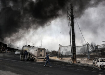 Dark smoke clouds engulf destroyed vehicles near an ongoing fire following an overnight airstrike on the Shahran oil refinery in northwestern Tehran.