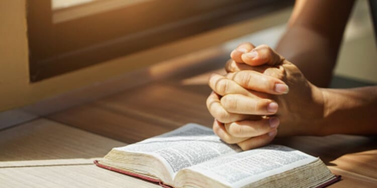 Hands on the Bible in a prayerful position.