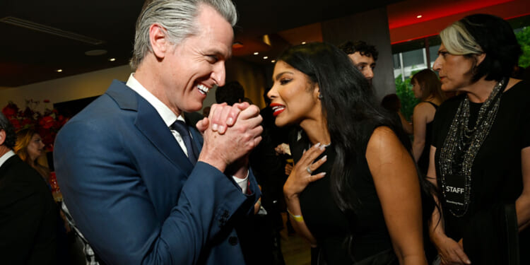 Gavin Newsom clasps his hands with glee while talking to Olivia Igbokewe Curry.