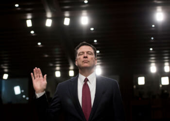 James Comey, with his eyes closed, raises right hand before giving congressional testimony.