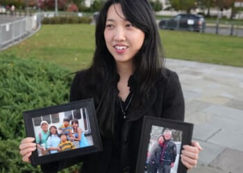 Grace Jin Drexel, the daughter of detained Chinese pastor Jin Mingri, holds up framed photos of Mingri and his family in Washington, DC on Oct. 30, 2025.