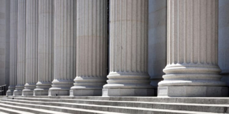 Pillars of a building stand on a base of stairs.