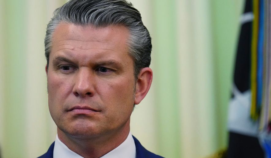 Defense Secretary Pete Hegseth listens as President Donald Trump speaks before signing a proclamation in the Oval Office at the White House, Tuesday, May 5, 2026, in Washington. (AP Photo/Jacquelyn Martin)