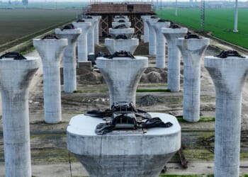 The unfinished high speed rail concrete columns stand in a vast green field.