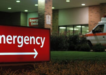 An emergency room entrance at night with an ambulance parked out front.