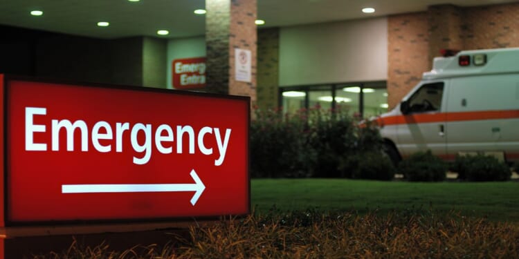 An emergency room entrance at night with an ambulance parked out front.