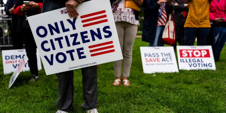 Attendees hold 'Only Citizens Vote' signs at a rally.
