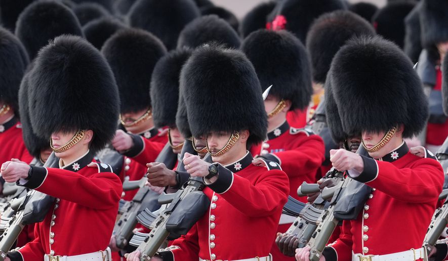 Members of the Guards march ahead of Britain's King Charles III and Queen Camilla leaving Buckingham Palace to attend the State Opening of Parliament at the Palace of Westminster in London, Wednesday, May 13, 2026.(AP Photo/Kin Cheung)