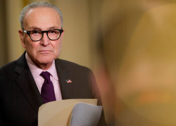 A dour-looking Chuck Schumer holding a file.