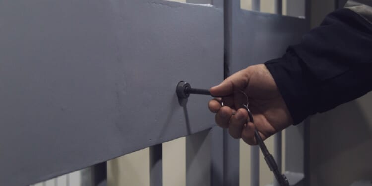 A photo illustration shows a hand using a key to open a barred door.