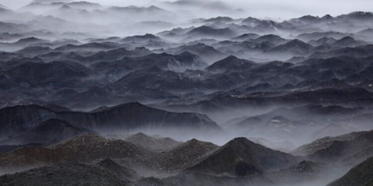 Mountains stand in swaths of fog.