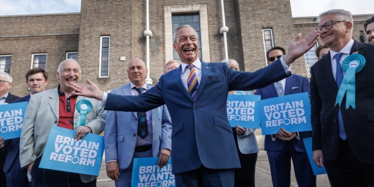 Nigel Farage smiling surrounded by Reform UK party members