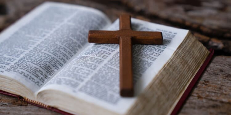 Crucifix sits at an angle on an opened Bible.