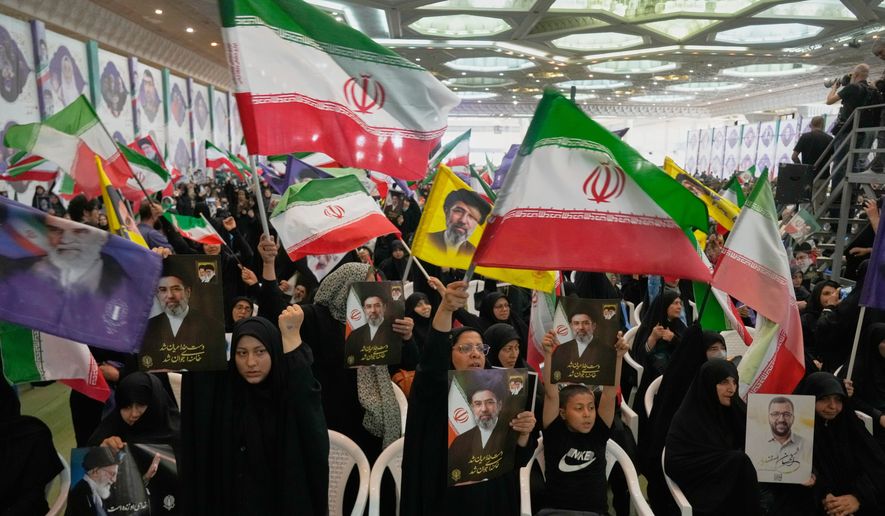Government supporters hold Iranian flags and pictures of Iran's Supreme Leader, Ayatollah Mojtaba Khamenei, during a ceremony honoring the armed forces and those killed in the war with Israel and the U.S. at the Imam Khomeini Grand Mosque in Tehran, Iran, Sunday, May 24, 2026. (AP Photo/Vahid Salemi)
