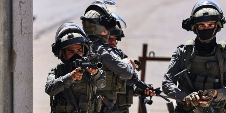 A member of the Israeli security forces aims his weapon while patrolling during a military raid in the Qalandia refugee camp, south of Ramallah in the Israeli-occupied West Bank, on May 11, 2026.