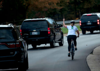 Juli Briskman shows her middle finger as a motorcade with US President Donald Trump on October 28, 2017.